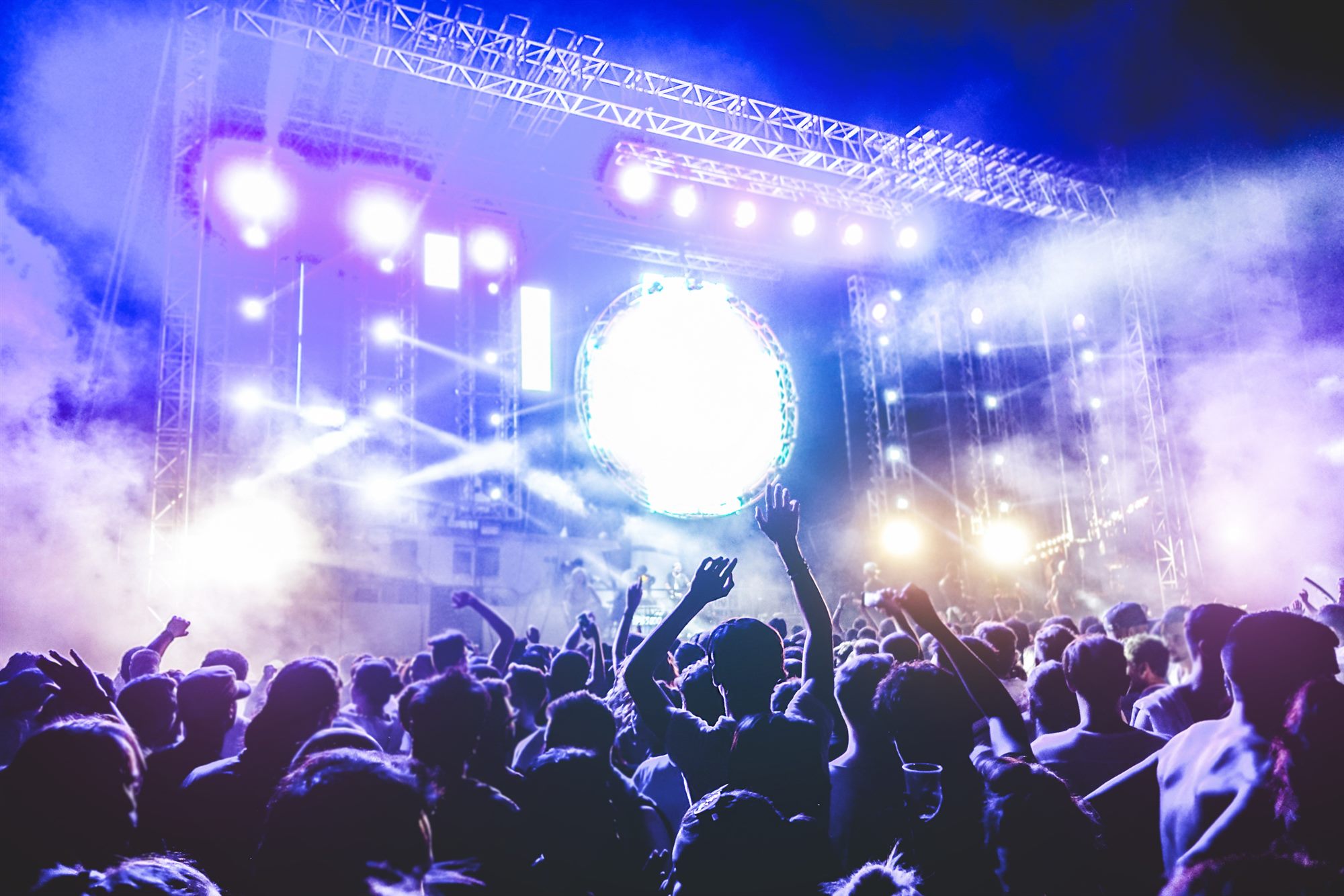 Stage lights over a standing concert crowd
